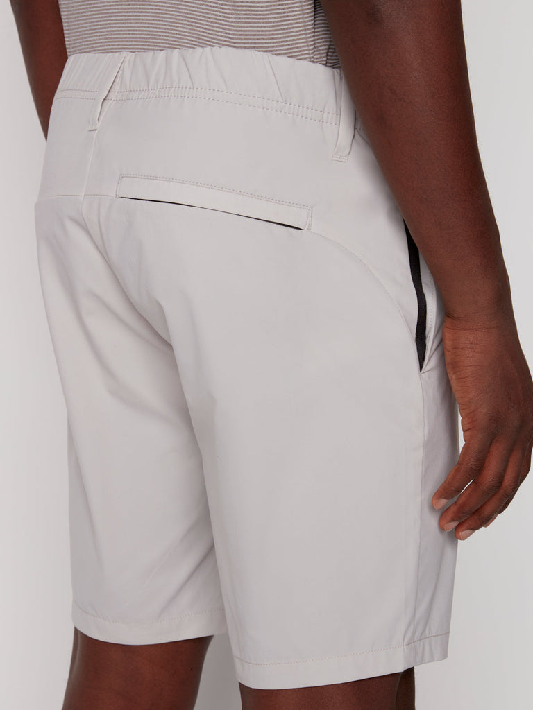 A person wears the ANTHONY MENS SHORT - BONE by Projek Raw, featuring an elastic waistband, back pocket, and black trim detail on the side pocket. Their right hand is relaxed by their side.
