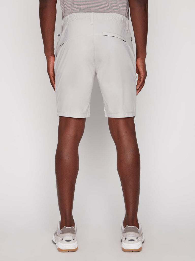 A person stands facing away from the camera, wearing Projek Raw ANTHONY MENS SHORT - BONE with a gray shirt and white sneakers, set against a plain white background.
