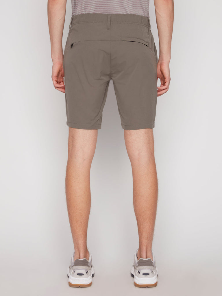 Back view of a person wearing Projek Raw ANTHONY MENS SHORT - MOSS, a gray tucked-in shirt, and white sneakers with gray soles, standing against a plain white background.