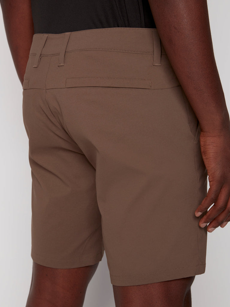 A person is shown from the back, waist down, wearing Projek Raws PAUL MENS SHORT - COFFEE and a black shirt, with one hand resting at their side.