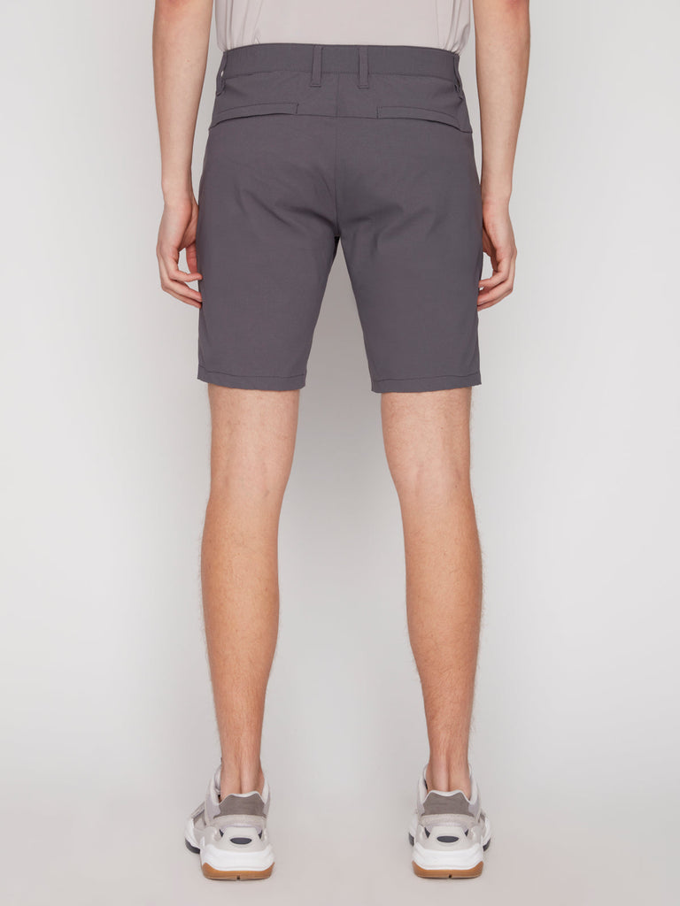 A person is shown from behind against a plain white background, wearing Projek Raw’s PAUL MENS SHORT - GREY, paired with a light shirt and white sneakers.