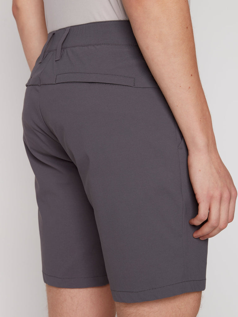 A person is shown from the back wearing Projek Raws PAUL MENS SHORT - GREY, paired with a light gray shirt, standing against a plain light background with one arm relaxed by their side.