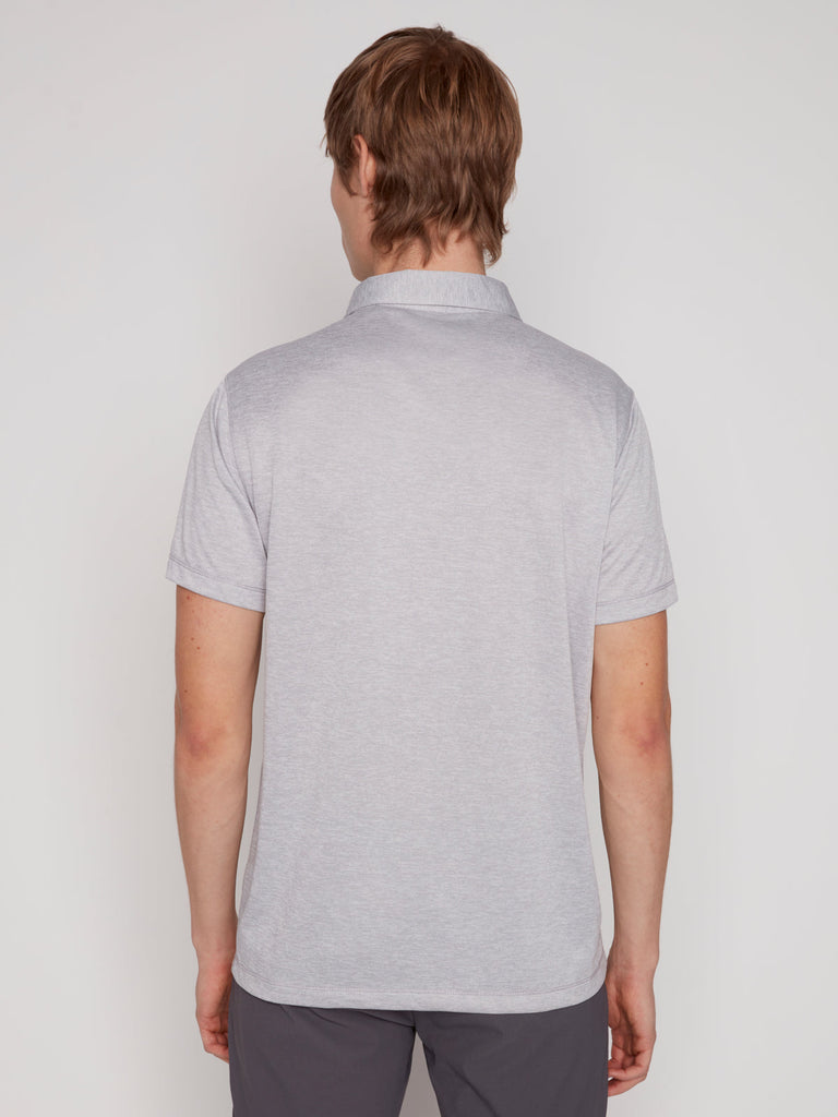 A person with light brown hair stands facing away from the camera, wearing the Projek Raw MICHAEL MENS POLO in light grey and dark gray pants against a plain white background.