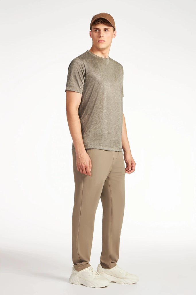A young man in a brown cap, gray t-shirt, TECH APPAREL MENS FLUX 2.0 PANT WITH DRAWCORD WAIST, and white sneakers stands against a white background, looking slightly to the side.
