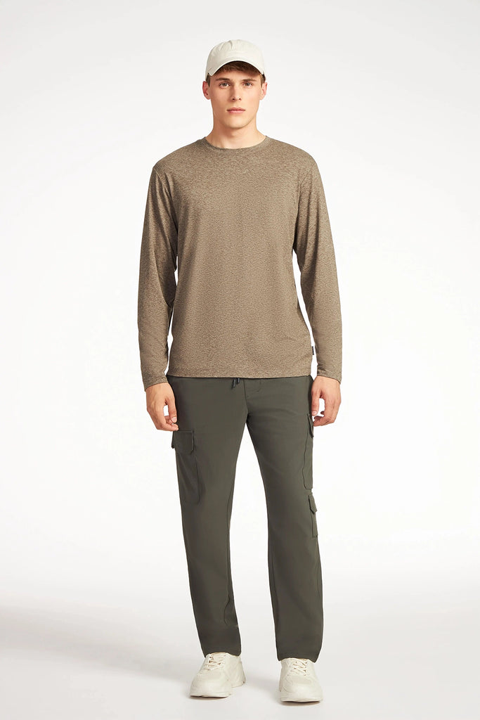 A man faces forward against a plain white background, wearing a beige long-sleeve shirt, TECH APPAREL MENS DRI-FLEX CARGO PANT with utility pockets, white sneakers, and a light beige cap.