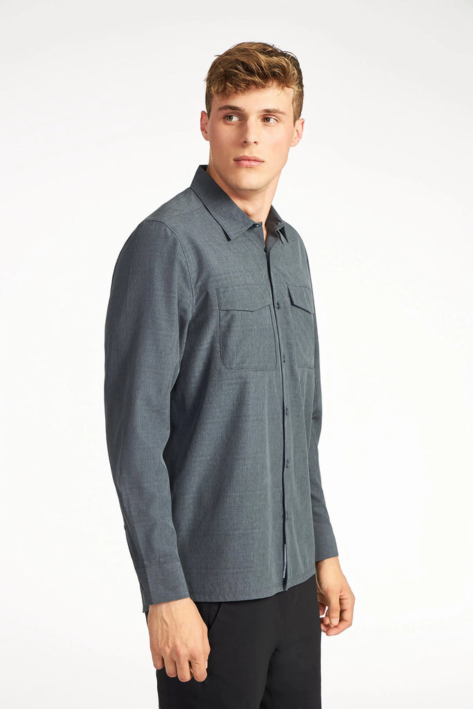 A young man with short light brown hair wears the TECH APPAREL MENS FOUR WAY STRETCH SHIRT, featuring two chest pockets, standing and looking slightly to his right against a plain white background.