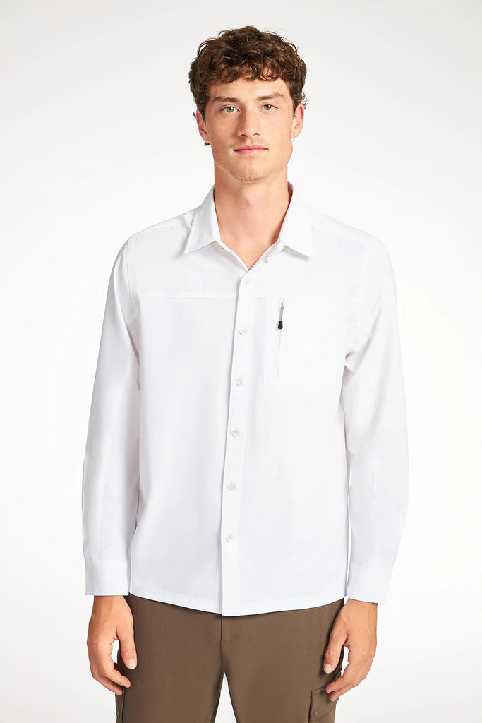 A man with short curly hair wears a TECH APPAREL MENS SOLID STRETCH RIPSTOP SHIRT with a pen in the chest pocket and brown pants, standing against a plain white background.