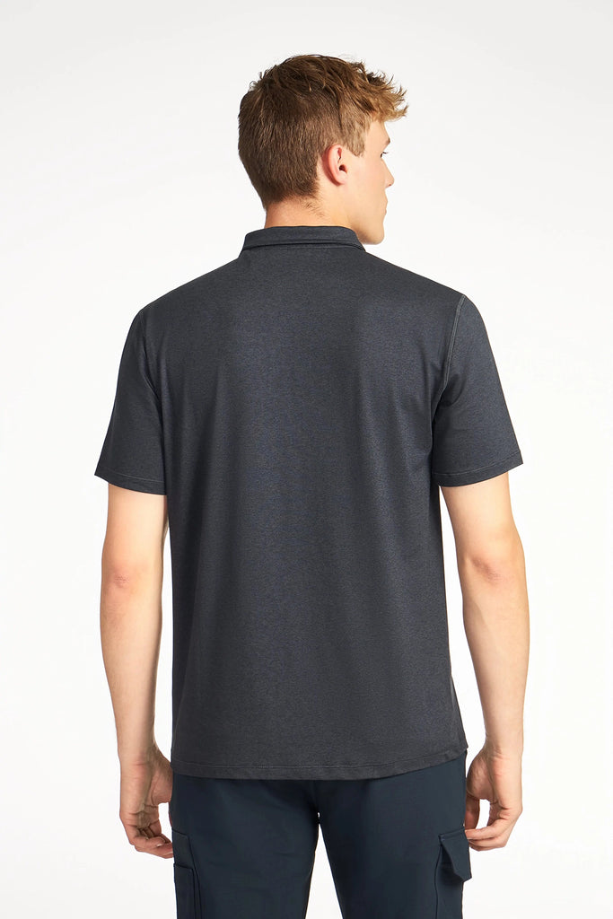 A man with short light brown hair is seen from behind wearing a dark gray MENS BRUSHED SPACE DYED POLO by TECH APPAREL, styled with dark pants against a plain white background.