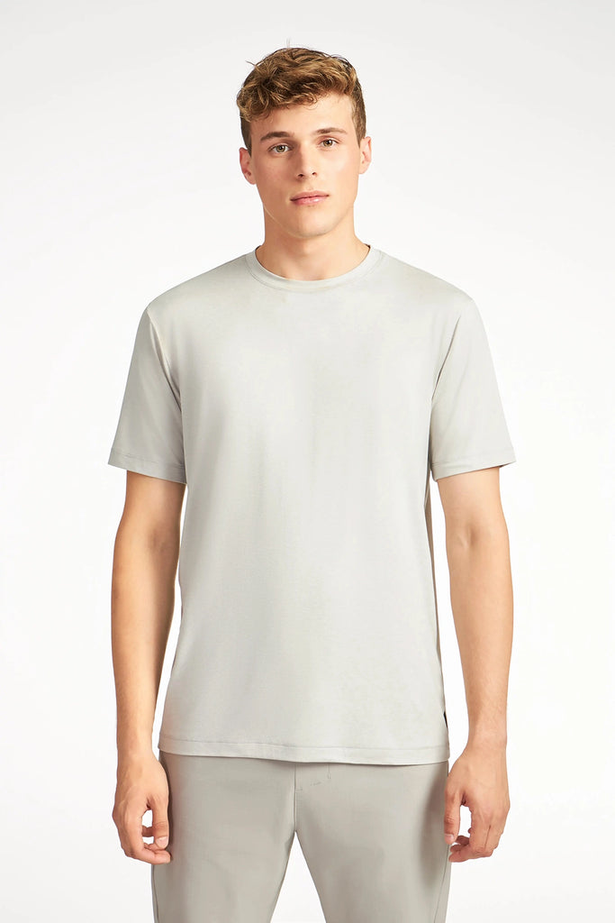 A young man with short light brown hair wears the TECH APPAREL MENS BRUSHED SPACE DYED T-SHIRT and matching pants, standing against a light background and looking directly at the camera with a neutral expression.