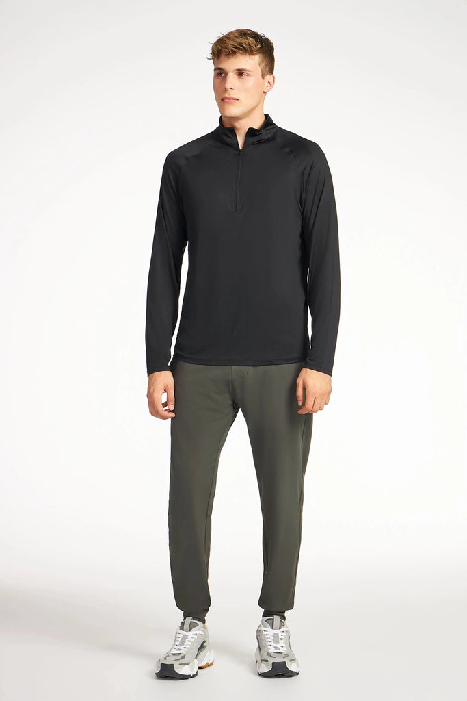 A person stands facing forward wearing a TECH APPAREL MENS BRUSHED MARLED MOCK-NECK PULLOVER in black, olive green jogger pants, and white sneakers against a plain white background.