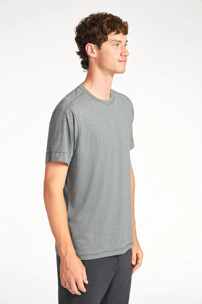 A young man with short brown hair stands sideways, wearing a TECH APPAREL MENS BRUSHED MARLED T-SHIRT in light gray and dark pants, posed against a plain white background.