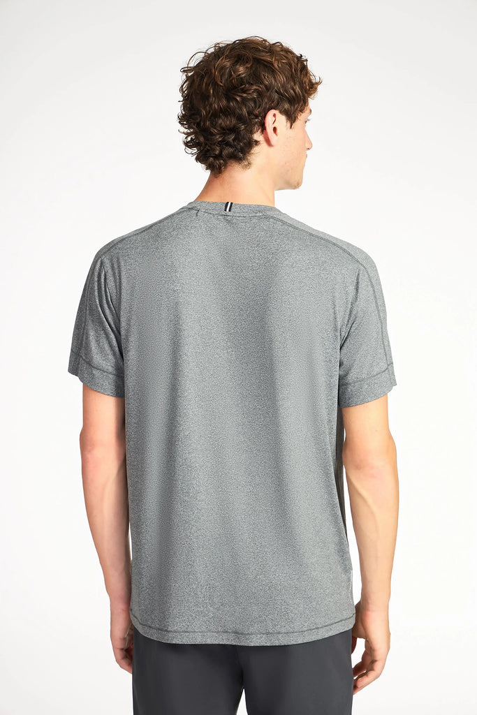A person with short curly hair wears the TECH APPAREL MENS BRUSHED MARLED T-SHIRT in heather gray and dark shorts, facing away from the camera against a plain white background.