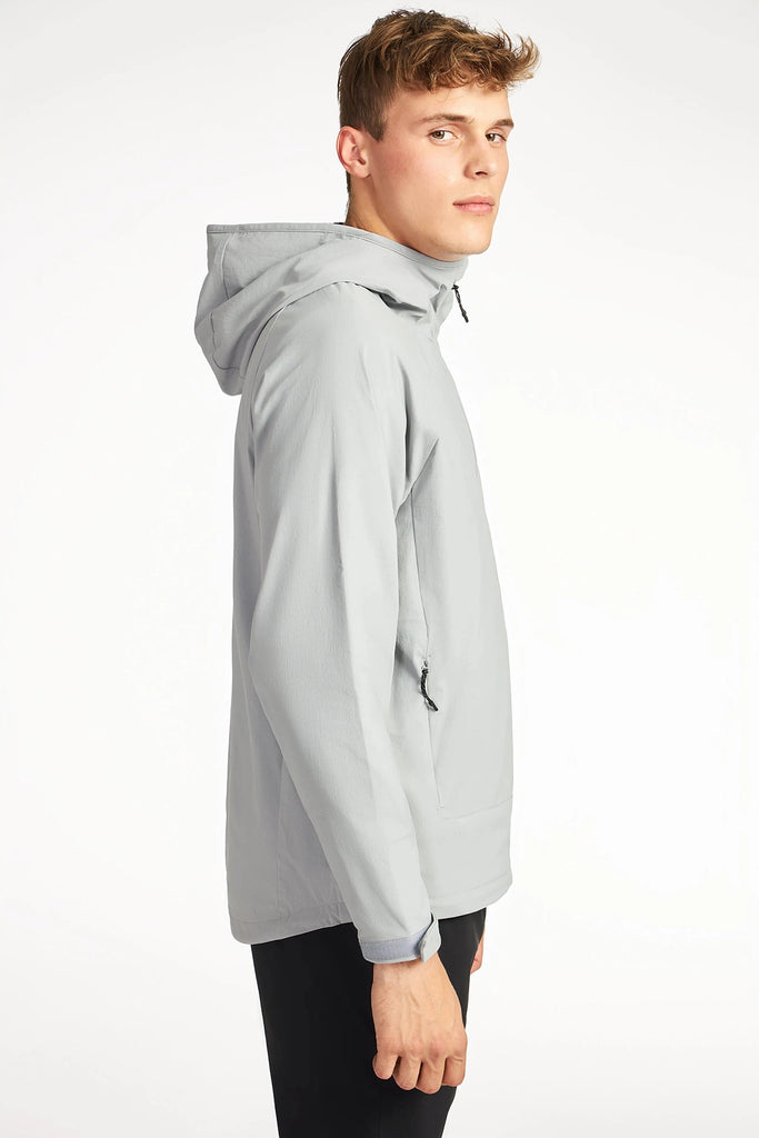 A young man models the TECH APPAREL MENS DRI-FLEX JACKET in light gray with black pants, standing sideways and looking over his shoulder against a plain white background.