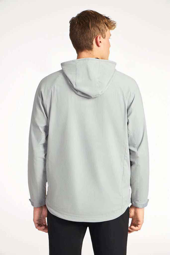 A person with short light brown hair, wearing the TECH APPAREL MENS DRI-FLEX JACKET in light gray and black pants, stands with their back to the camera against a plain white background.