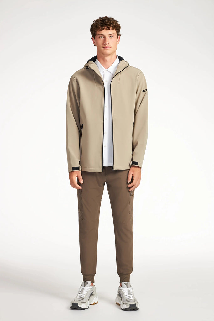 A young man faces forward in a TECH APPAREL MENS BONDED FLEECE JACKET, paired with a white shirt, brown pants, and white sneakers, set against a plain white background.