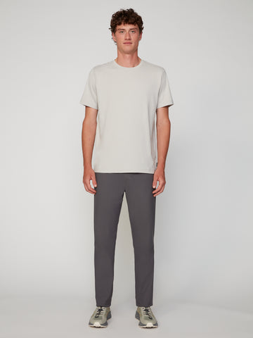 A man faces forward against a plain background, wearing a light gray short-sleeve T-shirt and TECH APPAREL MENS PULL-ON CHINO 247:TWILL PANT in dark gray, made from comfortable mechanical stretch twill.