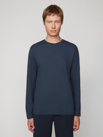 A young person with short light brown hair wears the TECH APPAREL MEN’S LONG SLEEVE CREW NECK IN BRUSHED SPACE-DYED JERSEY and dark pants, standing against a plain light gray background, facing forward with a neutral expression.