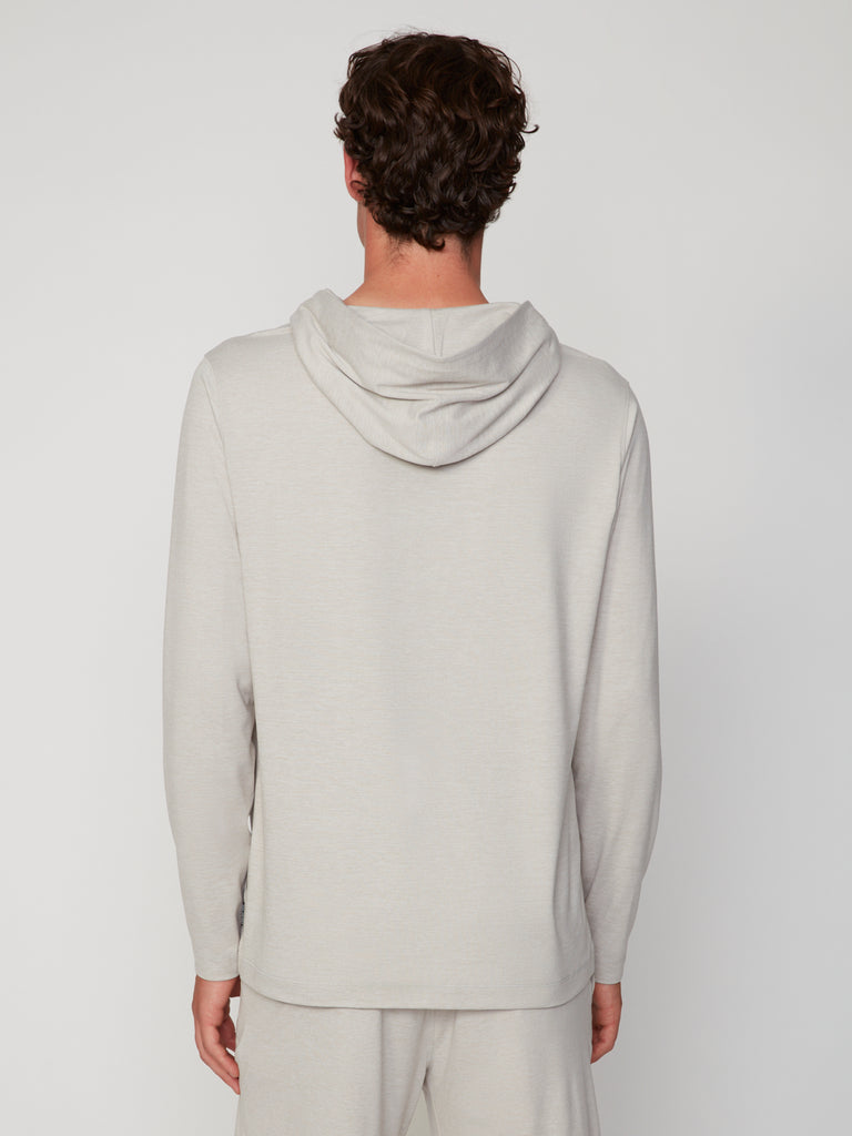 A person with short, curly brown hair models the TECH APPAREL MEN’S LONG SLEEVE HOODIE IN BRUSHED SPACE-DYED JERSEY and matching pants, shown from the back against a plain light background for breathable warmth.