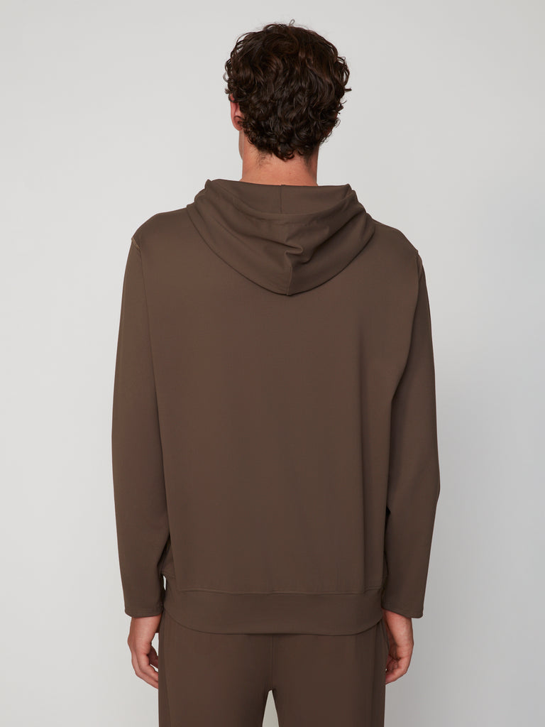 Seen from behind, a person with short curly brown hair wears the TECH APPAREL MEN’S TECH:SOFT CLASSIC FIT HOODIE and matching pants, standing against a plain light gray background. Soft knit fabric provides lightweight warmth for daily comfort.
