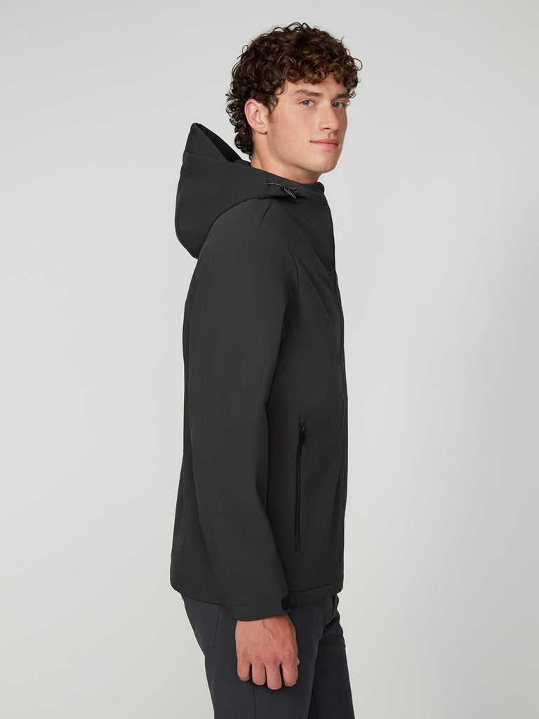 A young man with curly brown hair models the TECH APPAREL MENS BONDED FLEECE JACKET in black. He stands sideways, looking at the camera, against a plain light gray background.