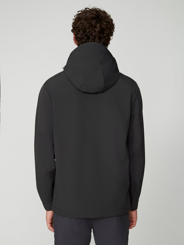 A person with curly hair is seen from behind, wearing a black TECH APPAREL MENS BONDED FLEECE JACKET and dark pants against a plain light gray background.